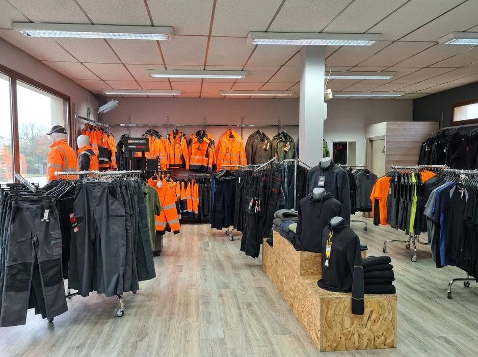 Intérieur d'un magasin spécialisé présentant des vêtements de travail professionnels suspendus sur portants